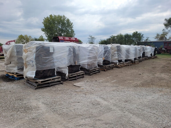 Large bags of firewood on pallets covered with plastic sheets